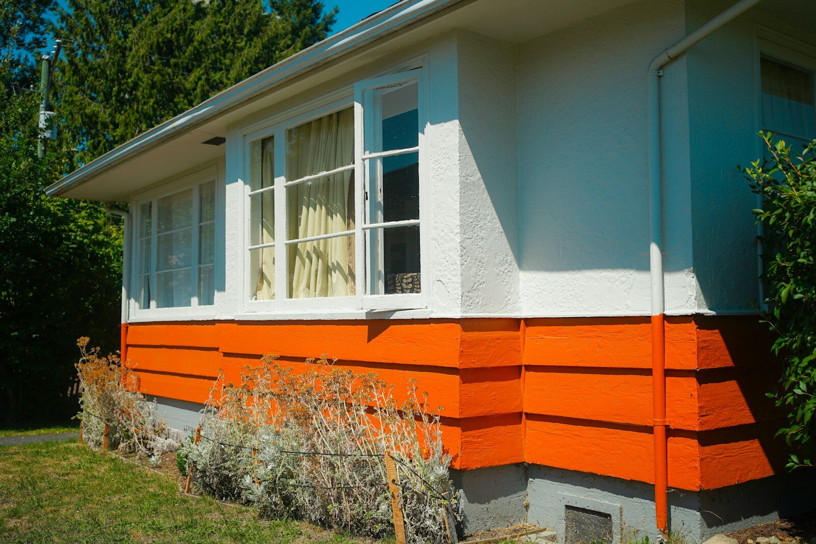 Fachada de casa blanca con la parte baja pintada de naranja intenso